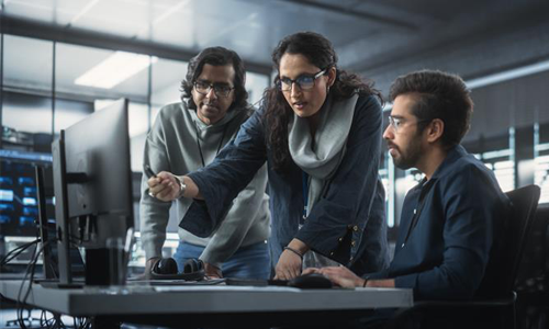 dos hombres y una mujer trabajando frente a una computadora