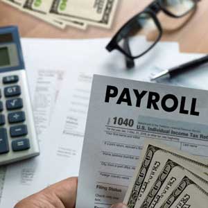 imagen de escritorio con planilla de payroll y dinero en primer plano